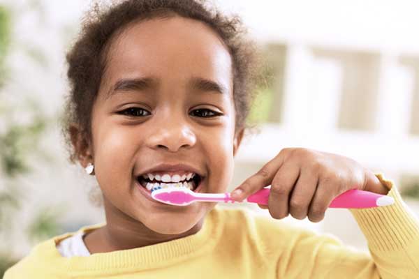 Ein braunhaariges Kind, dass die Zähne putzt.
