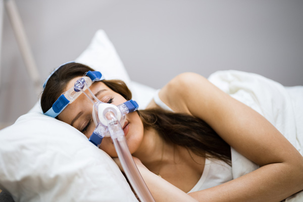 Eine Frau schläft mit einer CPAP-Maske während der Schlafapnoe-Therapie.