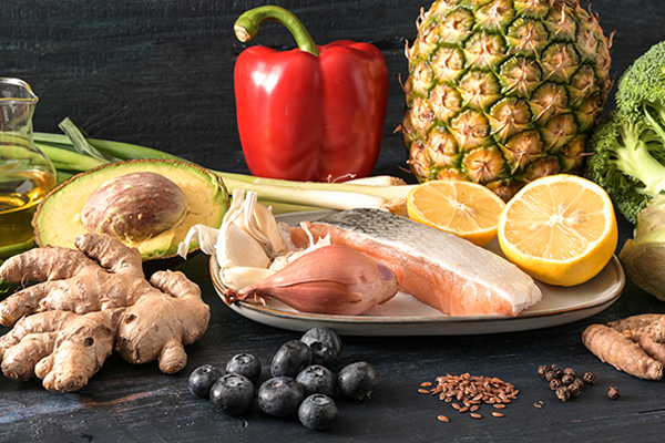 Frische Lebensmittel auf einem Tisch, darunter Lachsfilet, Avocado, Paprika, Ingwer, Blaubeeren, Brokkoli, Ananas, Zitrone und Gewürze. Frische Lebensmittel auf einem Tisch, darunter Lachsfilet, Avocado, Paprika, Ingwer, Blaubeeren, Brokkoli, Ananas, Zitrone und Gewürze.