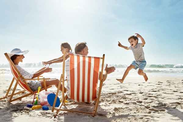 Familie am Urlaubsort am Strand, Kinder spielen im Sand. Reisemedizin-Grundausstattung wichtig, um Reisekrankheit vorzubeugen. Familie am Urlaubsort am Strand, Kinder spielen im Sand. Reisemedizin-Grundausstattung wichtig, um Reisekrankheit vorzubeugen.